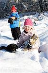 Children and dog collecting wood in snow