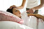 Mother checking daughter's temperature, caressing forehead