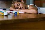 Girl resting head on arms asleep at desk