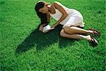 Young woman lying on grass reading book