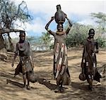 Turkana filles reviennent chez eux après un point d'eau avec des contenants d'eau en bois. Leurs manteaux est orné de perles de verre de peau de chèvre.
