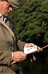 Wales; Wrexham. A trout fisherman selects his fly to fish on the River Dee.