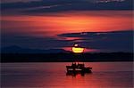 Zambia,Lower Zambesi National Park. Guests watching the sun rise over the Zambezi River from a boat.