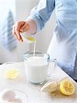 Frau gießt Zitronensaft in Milch