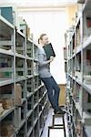 Woman stands on stool in library