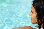 Young woman in swimming pool, looking away in thought