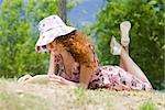 Young woman lying on stomach reading outdoors