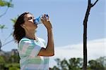 Woman outdoors, drinking water from bottle