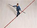 Man balancing on thin red line with pole