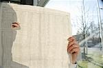 Man spying through hole in newspaper