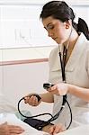 Nurse using blood pressure gauge on patient