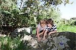 Two boys leaning on rock