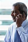 Head shot of mature Indian business man talking on phone