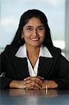 Indian business woman sitting at desk with hands folded