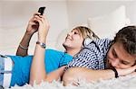 Teenager couple lying on carpet and listening to music, low-angle view