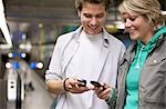 Teenagers changing phone numbers at train station, waist up