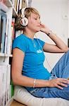 Young woman using headphones, side view