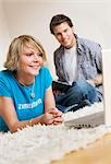 Teenager couple using media in living room, slanted view