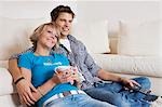 Séance de couple adolescent en face du canapé et regarder la télévision, format horizontal