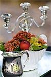 Candleholder, flower vase and cannikin on a glass table, close-up