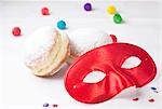 Red carnival mask, doughnuts and confetti, close-up