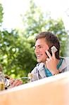 Young man talking on mobile phone and eating, low angle view