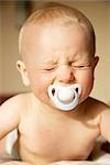 Baby boy with dummy in his mouth crying, portrait