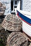 Crab pots and potting boat surrounded by traditional housing at Mousehole, Land's End, Cornwall, England