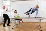 Businessman jumping over table