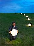 Man with illuminated ball on a meadow