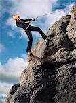 Businesswoman Climbing up Cliff