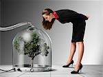 Businesswoman looking at Tree inside Pressurized Glass Dome