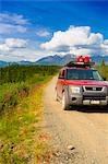 Car travelling on Nabesna Road in Wrangell Saint Elias National Park with the  Mentasta Mountains in the background, Southcentral Alaska, Summer