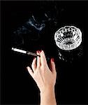Weibliche Hand mit Zigarette im Halter und Aschenbecher