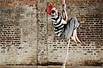 Young girl dressed up as pirate, climbing rope