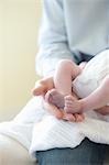 Father holding feet of two week old baby