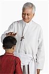 Priest blessing a boy and smiling