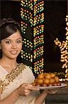 Woman holding sweets in a plate and smiling