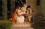 Couple placing oil lamps on doorstep with their children