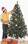 Man decorating a Christmas tree and smiling