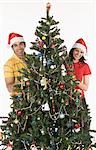 Portrait of a couple decorating a Christmas tree and smiling