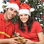 Portrait of a couple holding a Christmas present and smiling