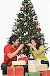 Couple toasting with wine glasses in front of a Christmas tree