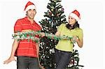 Couple playing in front of a Christmas tree and smiling
