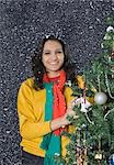 Woman decorating a Christmas tree and smiling