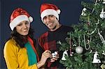 Couple decorating a Christmas tree and smiling