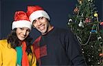 Portrait of a couple standing near a Christmas tree and smiling
