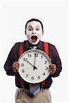 Close-up of a mime showing a clock