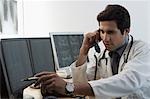 Male doctor examining an X-Ray and talking on the telephone