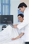 Male doctor showing ultrasound to pregnant woman